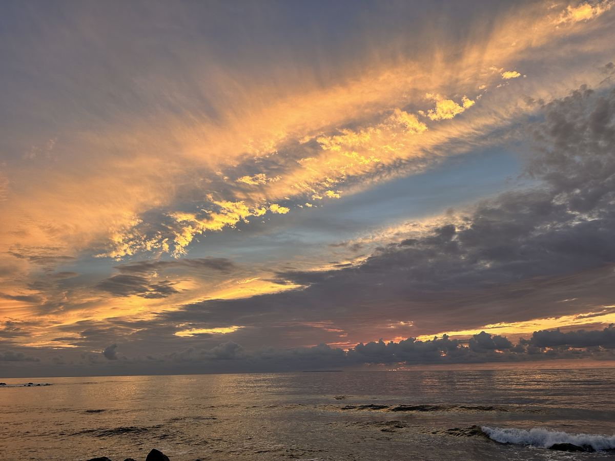雲の帯の間に青が一筋。海が金色に光っとる。