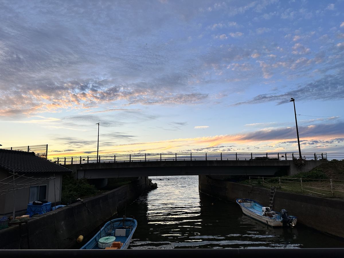 夕方の橋の上。青い空の裾に、金の帯が一本。