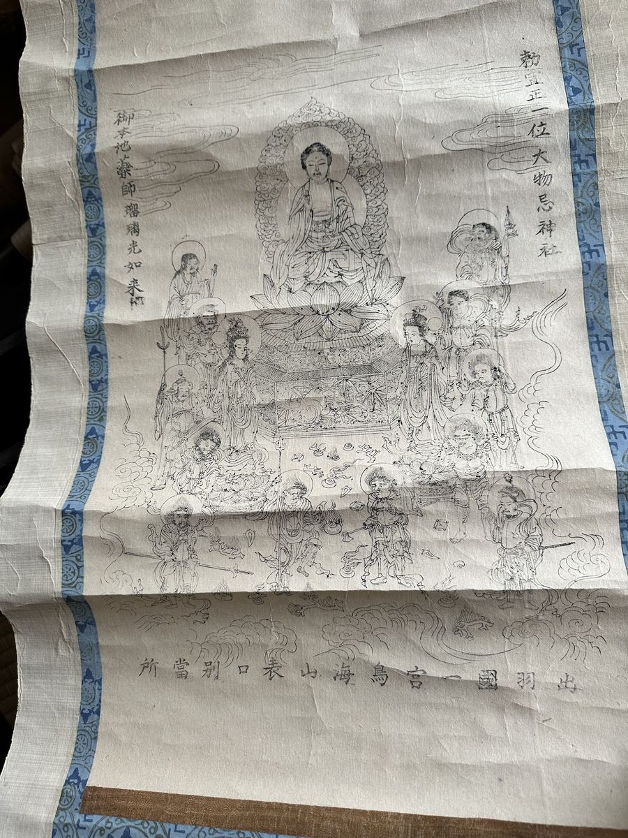 夜、家の片付けで出てきた古い掛け軸。神社の名前と薬師さんの名前が同じ紙に並んどる、百五十年前の書き方や。山の修行の九日前に、山の仏さんが出てくる。呼ばれとるんかもしれん。