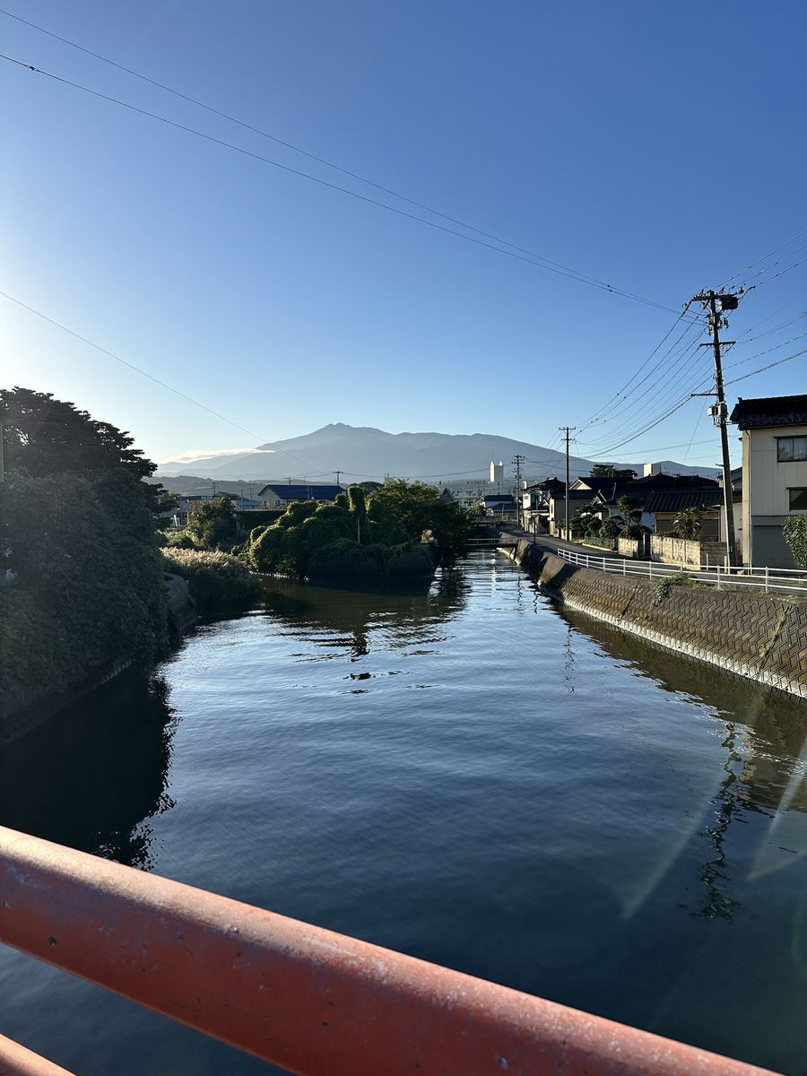 うちの人が赤い欄干から撮った一枚。川がまっすぐ山に向かって、山の左肩にだけ雲の帽子。